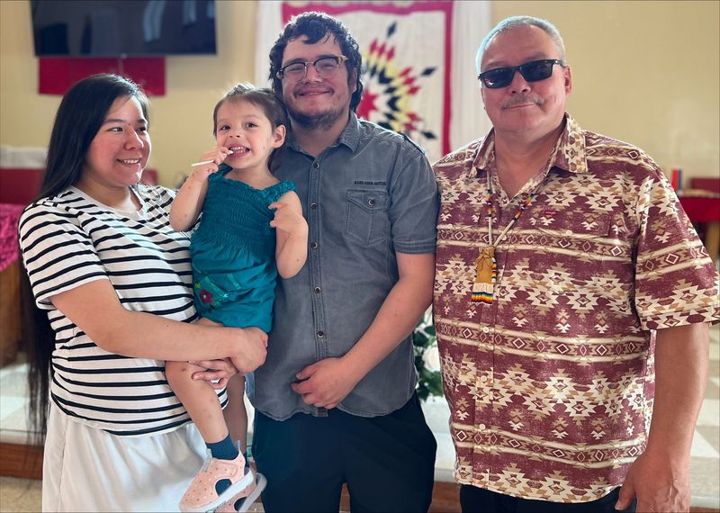 Felix Walker with a young family indoors beneath a star blanket.